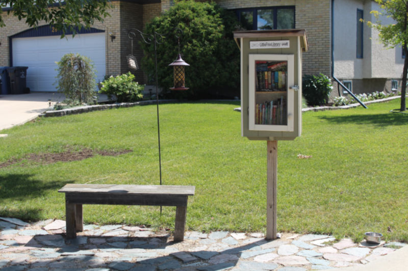 A Little Free Library with a bench to sit on beside it