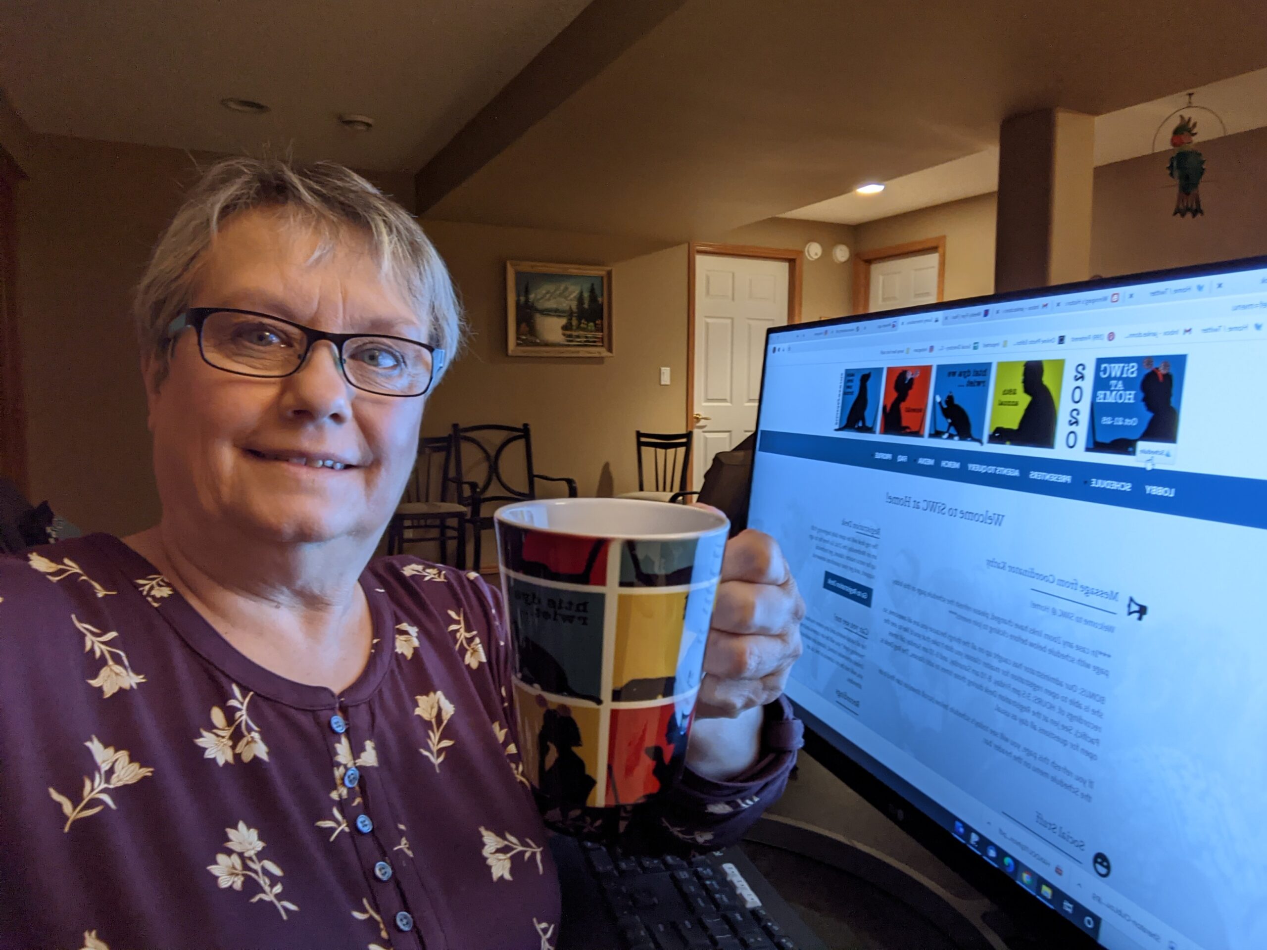 Woman sitting with mug of coffee in front of computer screen for virtual conference